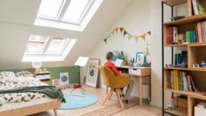 Chambre d'enfant sous les combles avec coin bureau, plafond en pente, fenêtres de toit VELUX.