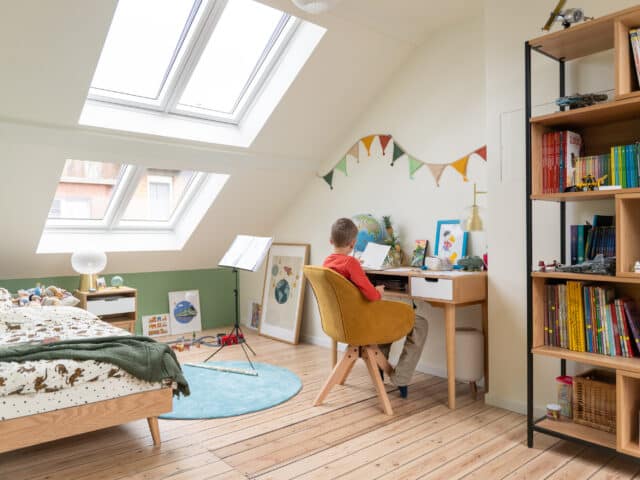 Chambre d'enfant sous les combles avec coin bureau, plafond en pente, fenêtres de toit VELUX.